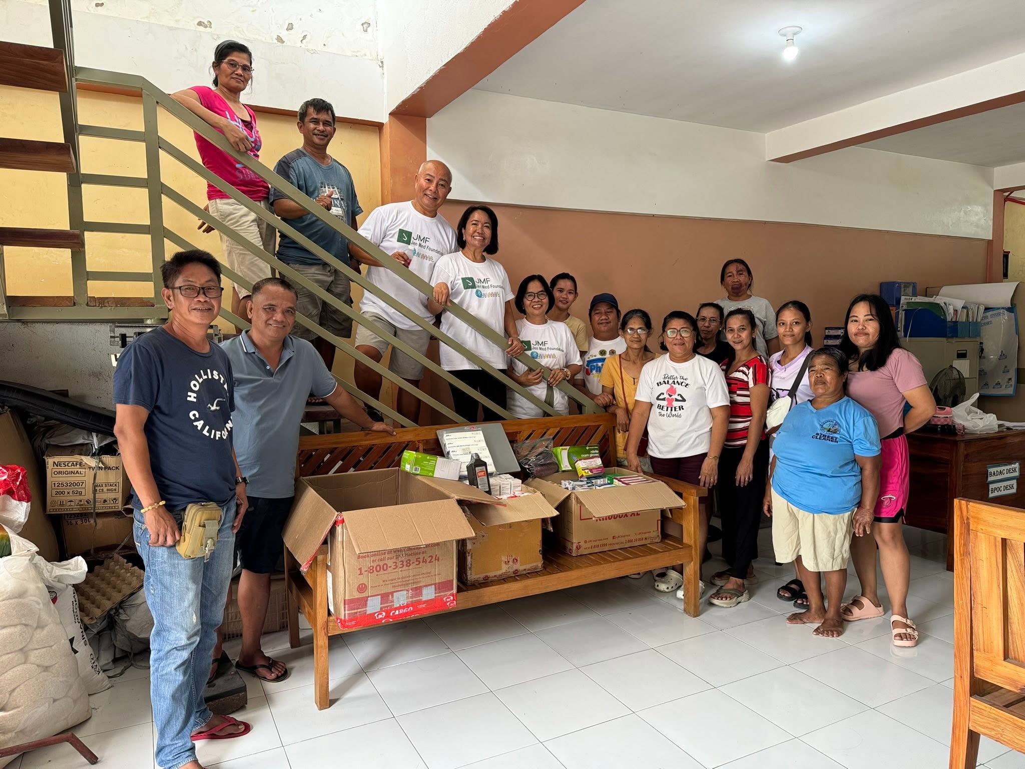 A large group gathers beside boxes of donated medicines.