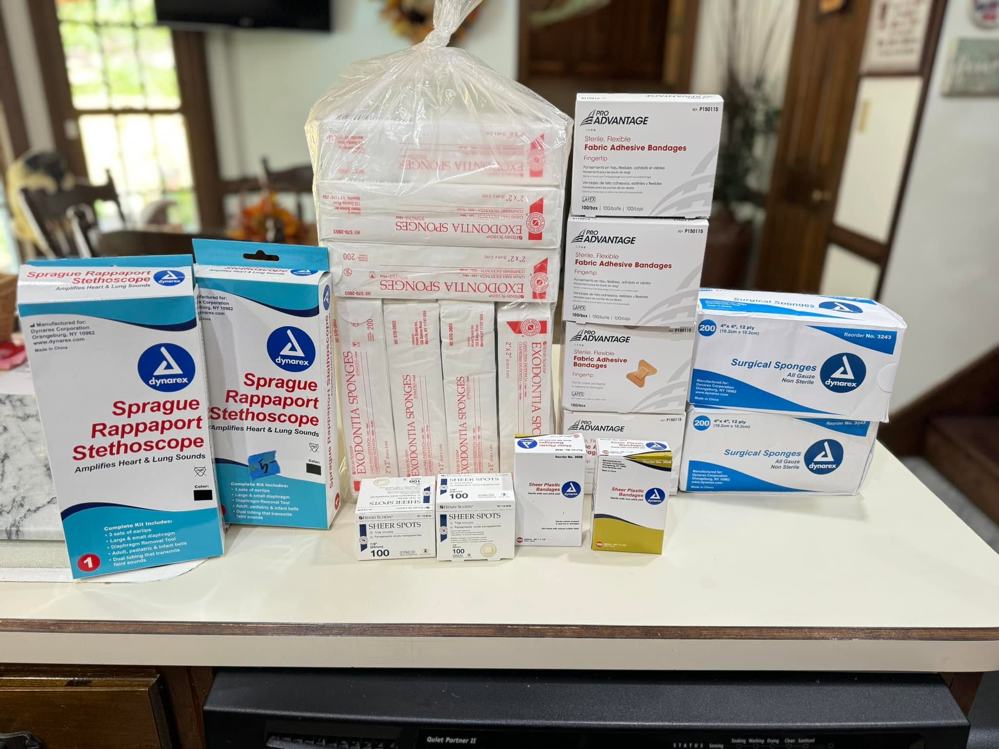 Medical supplies and packaged stethoscopes are arranged on a table.